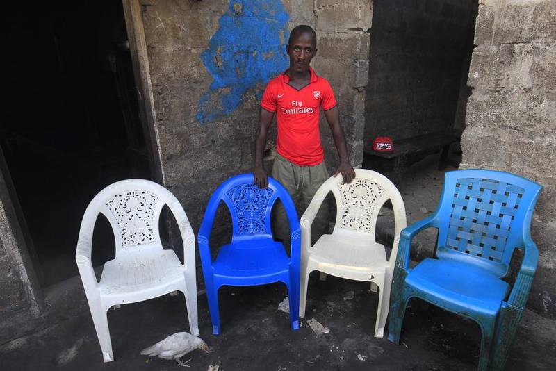 Mohammed Kromah, an Ebola survivor, poses for a family portrait at his home in West Point, Monrovia, Liberia. The empty chairs symbolise his wife and children, who died of the Ebola virus during an outbreak of the disease in 2014. Ahmed Jallanzo / EPA