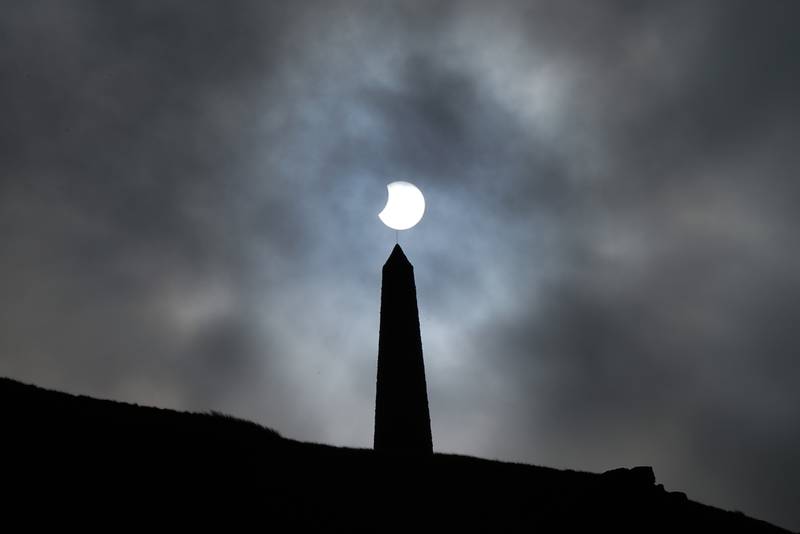 The sun broke through clouds during a partial solar eclipse visible over Stoodley Pike on Tuesday, a 387-metre hill in the south Pennines in West Yorkshire. PA