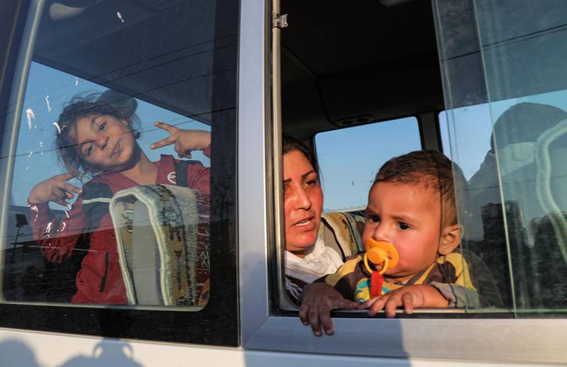 TOPSHOT - A woman holds a child while sitting in the back of a minibus transporting Syrian refugees who have been newly refugees by the Turkish military operation in northeastern Syria upon arriving at the Bardarash camp, near the Kurdish city of Dohuk, in Iraq's autonomous Kurdish region, on October 16, 2019. Some 500 Syrian Kurds have entered neighbouring Iraqi Kurdistan over the past four days fleeing a Turkish invasion now entering its second week, officials said. Iraqi Kurdistan previously hosted more than one million Iraqis who fled fighting with the jihadists of the Islamic State group between 2014 and 2017.
 / AFP / Safin HAMED
