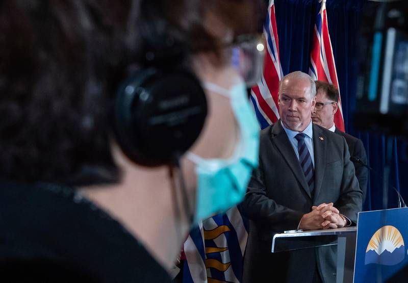 A camera operator wears a protective mask as British Columbia Premier John Horgan, Health Minister Adrian Dix, back right, and provincial health officer Dr. Bonnie Henry, hidden, take questions during a news conference about the provincial response to the coronavirus, in Vancouver, British Columbia.  AP