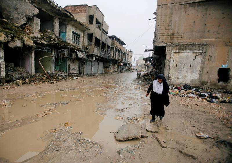A woman walks next to damaged shops in Mosul. Reuters