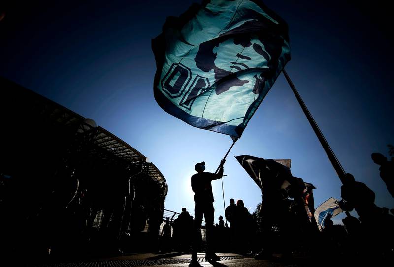 A man waves a flag at the effigy of late Argentinian football legend Diego Maradona, as people gather outside the San Paolo stadium in Naples to mourn the death of Maradona.  AFP