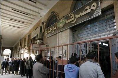 The Libyan president Muammar Qaddafi has maintained a 'closed' financial system that did not encourage foreign investment. Above, Libyans queue outside a bank to get cash in Benghazi.