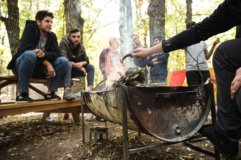 A group of young friends prepares tea around a campfire in Fneidek forest. Photo: Finbar Anderson / The National