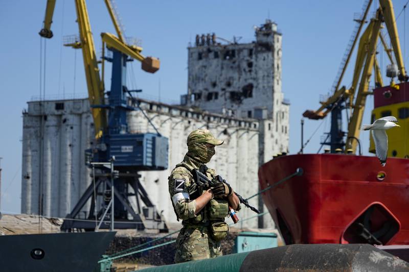 A Russian soldier guards a pier with grain stored in the background, at  Mariupol Sea Port in eastern Ukraine. AP