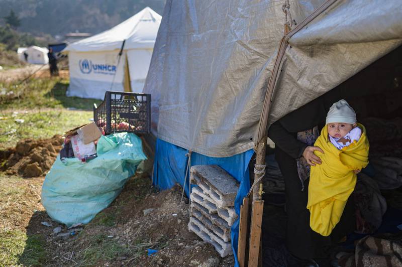 A woman holds her baby inside a tent in a camp in Antakya, Hatay. AFP