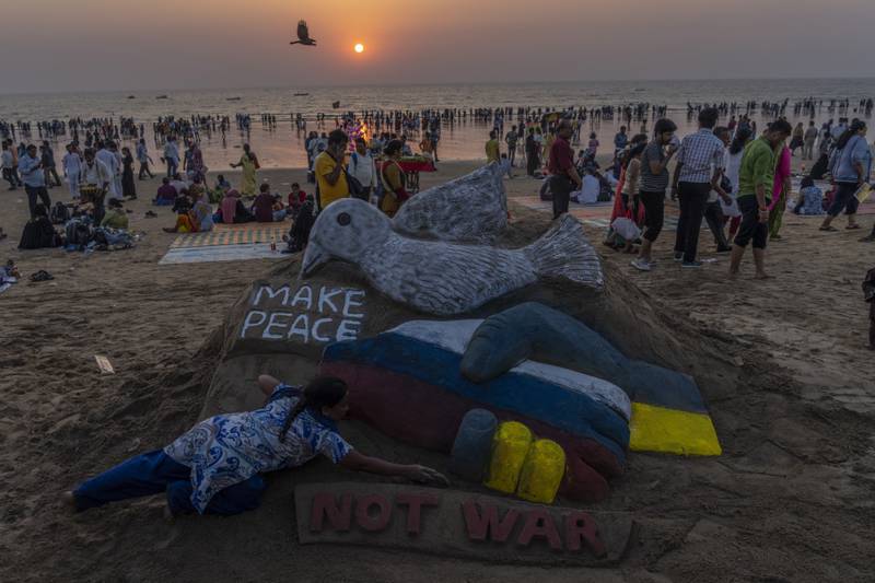 An Indian artist makes a sand sculpture calling for peace on Juhu beach in Mumbai. AP