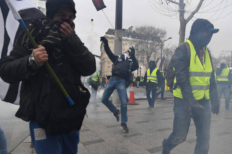 A protestor sends back a tear gas canister near the Arc de Triomphe in Paris on December 8, 2018. AFP