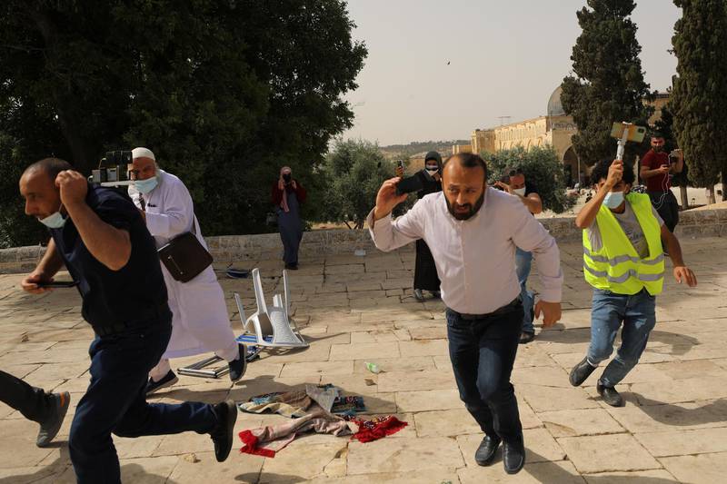 Palestinians run for cover during clashes with Israeli police at the compound that houses Al Aqsa Mosque. Reuters