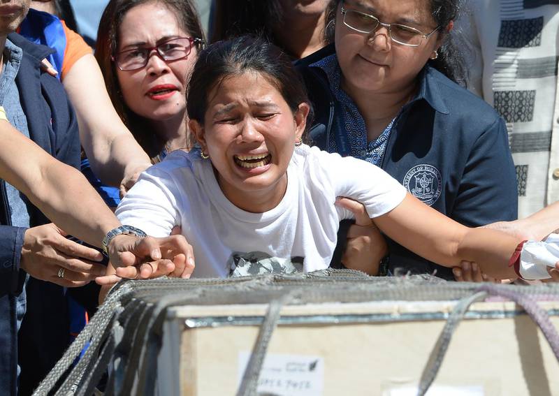 Jessica (C), sister of Filipina worker Joanna Demafelis whose body was found inside a freezer in Kuwait, cries in front of the wooden casket containing her sister shortly after arriving at the international airport in Manila on February 16, 2018.
The Philippines on February 12 expanded a ban on its citizens working in Kuwait after President Rodrigo Duterte angrily lashed out at the Gulf state over reports of Filipino workers suffering abuse and exploitation. Authorities say 252,000 Filipinos work in Kuwait, many as maids, yet domestic workers there are not covered by ordinary labour legislation. / AFP PHOTO / TED ALJIBE