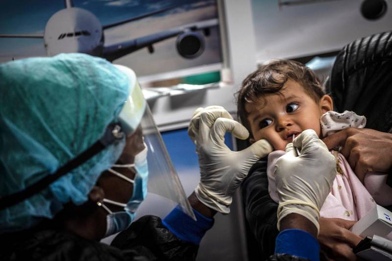 A health worker collects a sample for a Covid-19 test from a baby who arrived in a flight from Mexico at the Jose Marti International Airport in Havana, Cuba. AP Photo