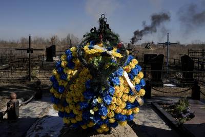 Smoke from shelling rises behind a wreath at a cemetery in Vasylkiv, south-west of Kyiv. AP