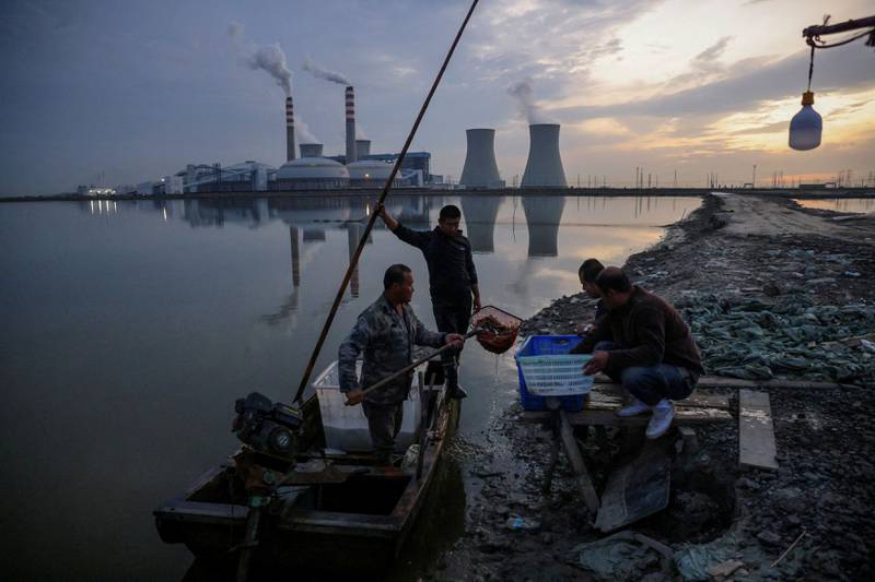 Fishermen bring in their catch from a lake in front of a power plant of the State Development and Investment Corporation outside Tianjin, China, on October 14, 2021. By Thomas Peter,  Pulitzer Prize finalist for Feature Photography. Reuters