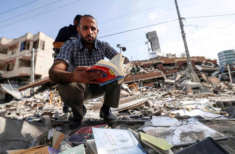 A Palestinian man holds a book he removed from under the rubbe of the Kuhail building which was destroyed in an early morning Israeli airstrike on Gaza City on May 18. AFP