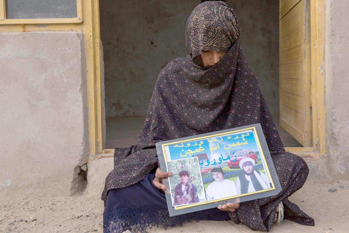 Covering her face, Khadija, 19, holds a photo of her three husbands: the Taliban fighter to the right, the police officer to the left, and her current husband in the middle. She lives outside of Helmand's provincial capital Lashkargar. Photo by Stefanie Glinski