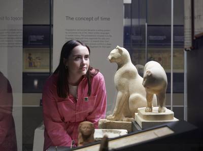 A visitor views Egyptian sculptures of cats. Photo: The Trustees of the British Museum
