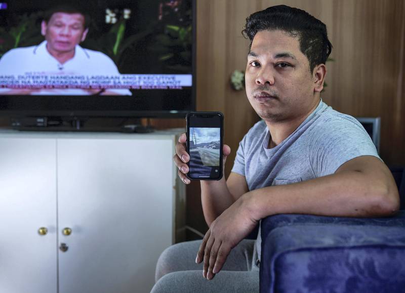 Abu Dhabi, United Arab Emirates, January 11, 2020.  Albert Tenorio, 28, a Filipino OFW (Overseas Filipino Worker) from Abu Dhabi monitors a  Filipino channel news program while showing some images of the ashfall damage at his home town. Albert is from Talisay, Batangas, which is only around 35 km from the Taal volcano shoreline.   Victor Besa / The NationalSection:  NAReporter:  Anam Rizvi