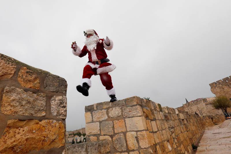 A man dressed as Santa Claus waves as he walks along Jerusalem's Old City Ottoman walls. AFP