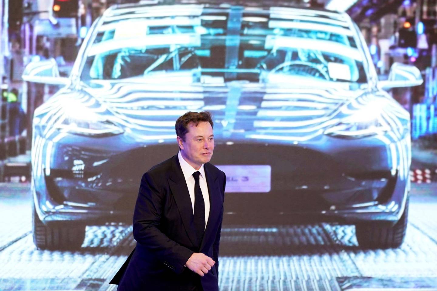 FILE PHOTO: Tesla Inc CEO Elon Musk walks next to a screen showing an image of Tesla Model 3 car during an opening ceremony for Tesla China-made Model Y program in Shanghai, China, January 7, 2020. REUTERS/Aly Song/File Photo