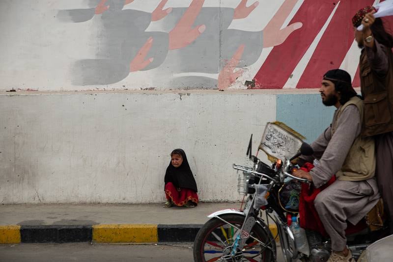 A girl cries on the pavement as men ride by on a motorbike, during celebrations in Kabul marking the first anniversary of Taliban's return to power. Getty 