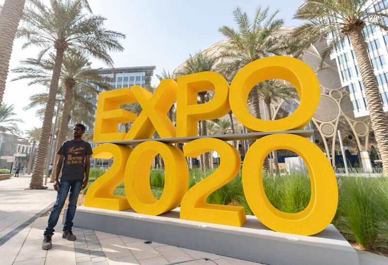 A person poses by the sign before the Dubai Expo 2020 opening ceremony.