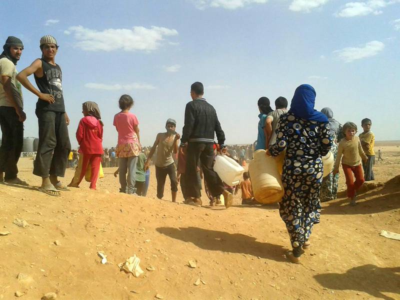 Syrian refugees gather for water at the Rukban refugee camp in Jordan's northeast border with Syria on Thursday, June 23, 2016. They had been cut off from supplies following Jordan's closure of the area after a car bomb attack launched from Ruqban killed six Jordanian troops and wounded 14 at dawn Tuesday. Two days later on Thursday, 32 water trucks drove to Ruqban and the smaller Hadalat camp with about 64,000 Syrians. (AP Photo)