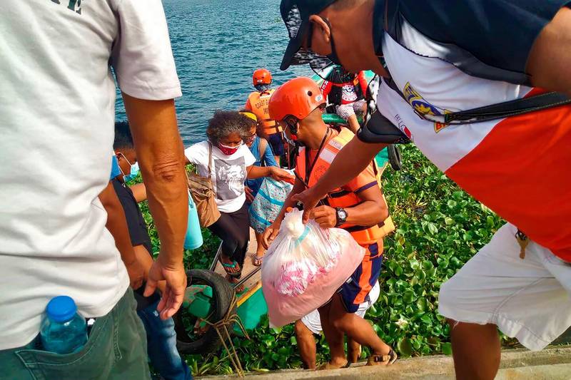 Families are evacuated by members of the Philippine Coast Guard to safer ground in Camarines Sur province, eastern Philippines. Philippine Coast Guard via AP