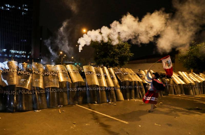 In the Peruvian capital on January 20, a demonstrator stands in front of riot police during the 'Take Over Lima' march to demonstrate against Peru's President Dina Boluarte, following the removal of former president Pedro Castillo. Reuters