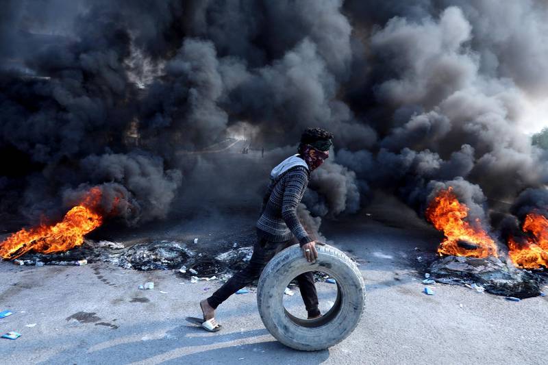 A protester pushes a tyre next to burning tires during ongoing anti-government protests in Kerbala, Iraq November 26, 2019. REUTERS/Abdullah Dhiaa al-Deen