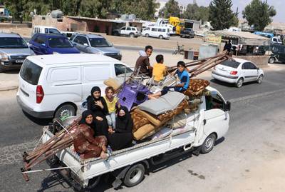 Displaced Syrians who fled from regime raids ride in a truck with their belongings arrive near a camp in Kafr Lusin near the border with Turkey in the northern part of Syria's rebel-held Idlib province.  AFP