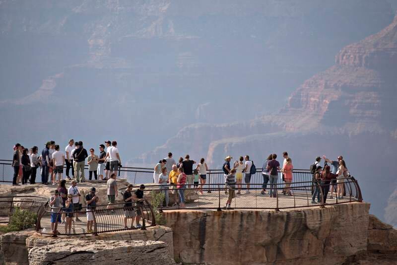 Visitors stand on an observation deck at Mather Point of Grand Canyon National Park in Grand Canyon, Arizona, U.S., on Wednesday, June 24, 2015. The Grand Canyon has seen a 20 percent increase in visitation through the first quarter of this year, according to a park spokesperson. Photographer: Daniel Acker/Bloomberg