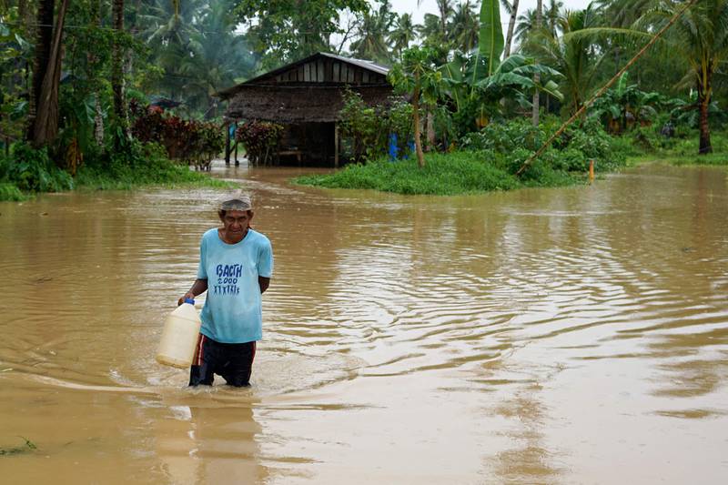 A resident wades through a flooded pathway next to his house in Abuyog.