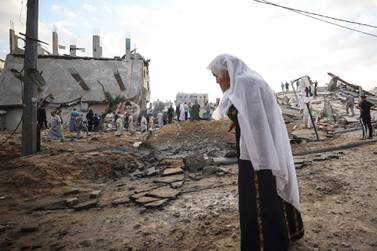 TOPSHOT - A Palestinian woman looks at destroyed buildings on the first day of the Eid al-Fitr holiday, which marks the end of the Muslim fasting month of Ramadan, in the northern Gaza Strip town of Beit Lahia, early on May 13, 2021. Israel's air force said it had launched multiple strikes overnight, targeting what it described as locations of Hamas, the Islamist group that controls Gaza. Meanwhile, incoming passenger planes scheduled to land at Israel's Ben Gurion airport near Tel Aviv were being diverted on May 13 to a southern airport amid rocket fire from Gaza, the airports authority said. / AFP / MAHMUD HAMS