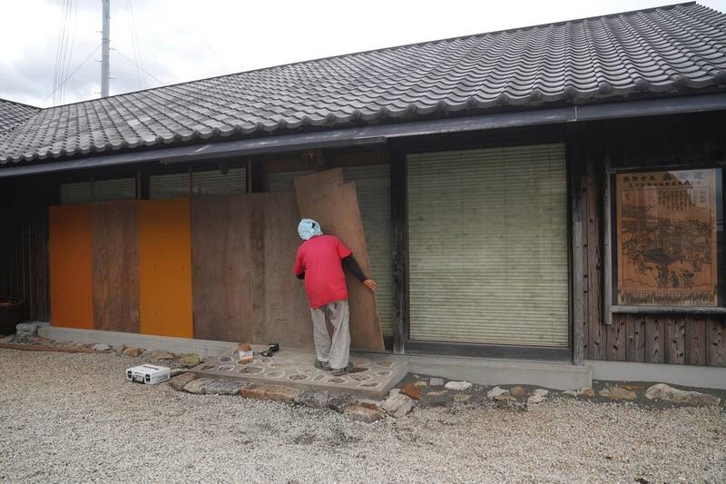 A man places wood boards to protect glasses from Typhoon Hagibis at a shop in Kumano, Mie Prefecture. AP Photo