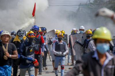 Anti-coup protesters retreat after discharging fire extinguishers towards a line of riot policemen in Yangon, Myanmar. AP