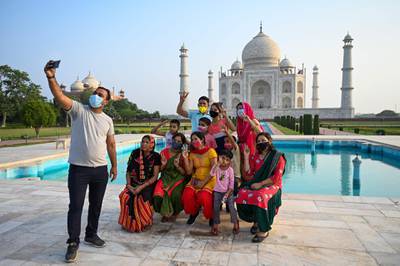 A group of tourists take souvenir photos at the Taj Mahal after it reopened to visitors. AFP