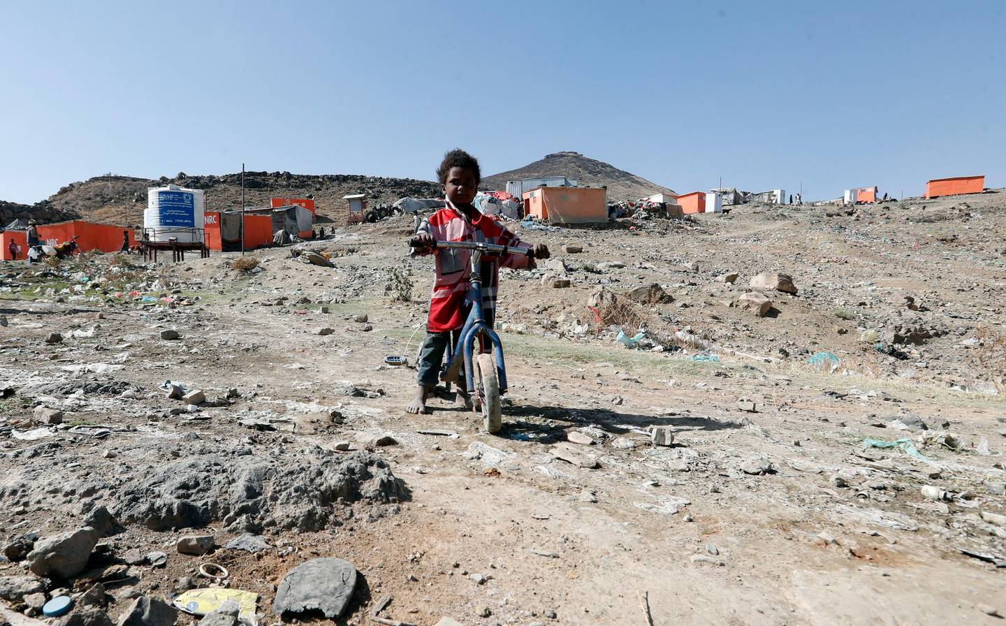 epa09045447 A displaced Yemeni child ride a bicycle at a camp for Internally Displaced Persons (IDPs) on the outskirts of Sana'a, Yemen, 01 March 2021. The five-year al-Azraqeen IDPs camp in the northern outskirts of Sana'a was rebuilt by the Norwegian Refugee Council in 2020 with orange wooden huts in place of the tents and small stone huts that the displaced people were using as their refuges. The camp hosts more than 60 displaced families, who were forcibly displaced by the escalating fighting in the northern areas of Yemen. The prolonged conflict has plunged Yemen into the world's largest humanitarian crisis with an estimated 80 percent of Yemen's 29 million-population are in need of humanitarian assistance, and led to the displacement of more than three million people.  EPA/YAHYA ARHAB