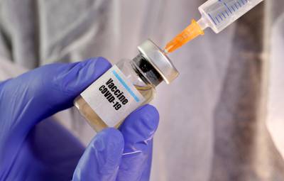 FILE PHOTO: A woman holds a small bottle labeled with a "Vaccine COVID-19" sticker and a medical syringe in this illustration taken April 10, 2020. REUTERS/Dado Ruvic/Illustration/File Photo