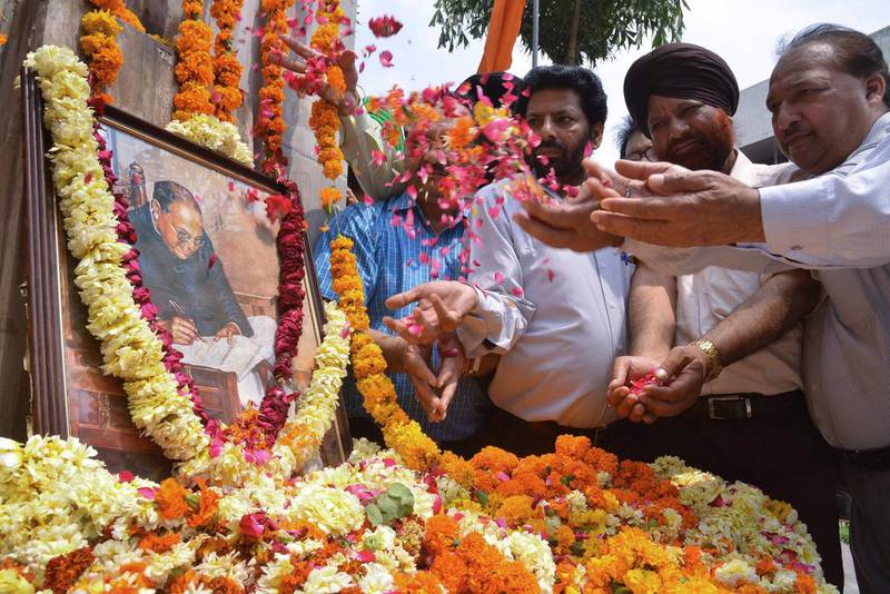 Members of the Shri Guru Ravidass Welfare Society place flowers around a photograph of Indian social reformer, B R Ambedkar to mark his 124th birth anniversay in Amritsar on April 14. AFP Photo

