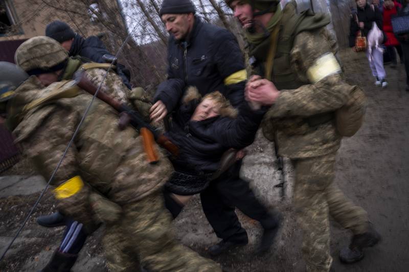 Ukrainian soldiers carry a sick woman as civilians flee Irpin, on the outskirts of Kyiv, after Russian attacks. AP Photo