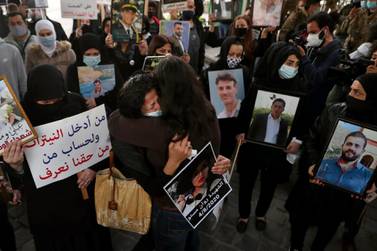 Relatives of victims of the Beirut port explosion hold portraits of their loved ones during a vigil. AP