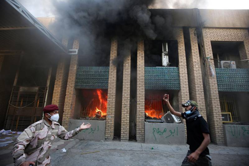 A member of the Iraqi security forces intervenes as demonstrators burn down the Kurdish Democratic Party's headquarters in the capital Baghdad. AFP