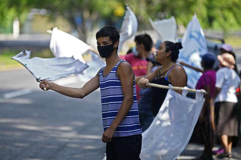 People flutter improvised white flags along a road to show their need for food during a mandatory quarantine imposed by the government against the spread of the new coronavirus in San Pedro Perulapan, El Salvador.  AFP