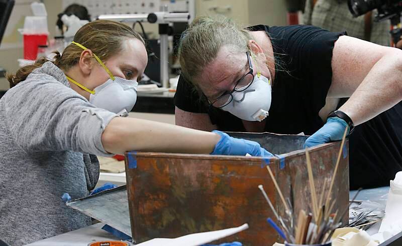 Sue Donovan, left, and Kate Ridgeway, right, dig into the artefacts inside the copper box time capsule. Photo via AP