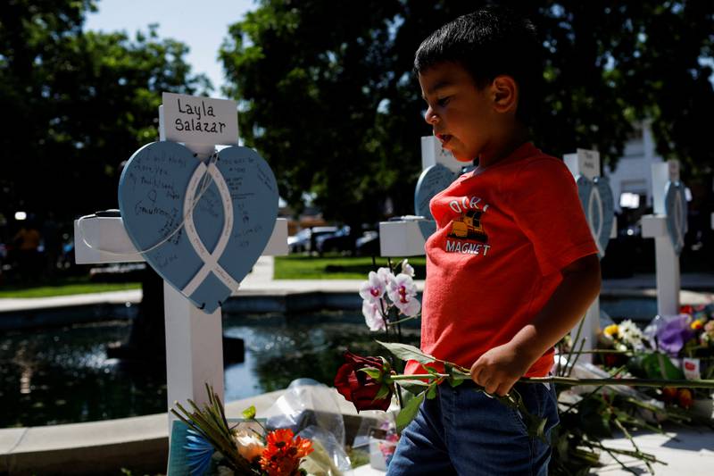A boy leaves a flower at a memorial in Town Square in front of the county courthouse, two days after a gunman killed nineteen children and two adults, in Uvalde, Texas, May 26.  Reuters