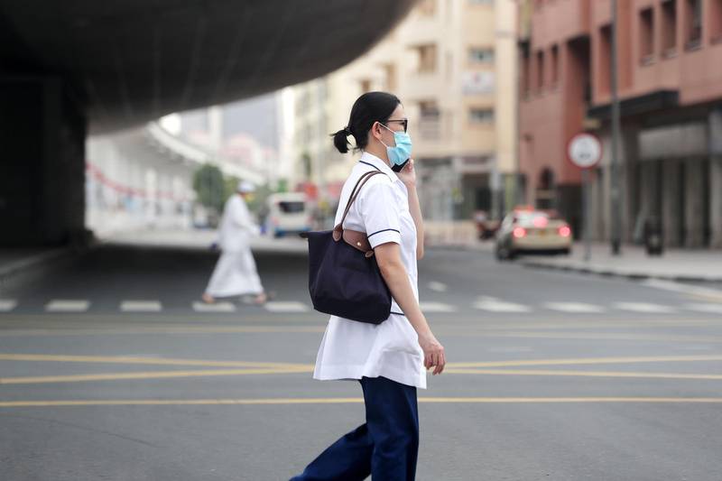 Dubai, United Arab Emirates - Reporter: N/A: A healthcare worker crosses an empty street in Bur Dubai while wearing a facemask due to the Corona outbreak. Monday, April 13th, 2020. Dubai. Chris Whiteoak / The National