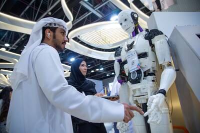 A man interacts with a robot at the Abu Dhabi Government stand