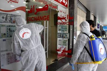Volunteers with Lebanon's Disaster Management Unit disinfect a currency exchange in the southern city of Saida on March 12, 2020 to prevent the spread of coronavirus. AFP