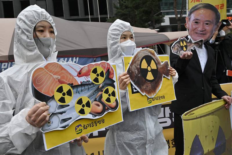 South Korean environmental activists wearing protective clothing and a mask of Japan's Prime Minister Yoshihide Suga hold pictures of fishes with radioactivity warning signs during a protest against Japan's decision on releasing Fukushima wastewater, near the Japanese embassy in Seoul. AFP