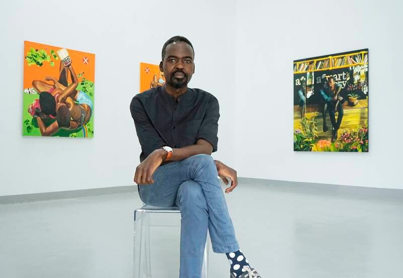 Daudi Karungi runs the Afriart Gallery in Uganda, as well as an art journal and the Kampala Art Biennale. He is shown here with works by Henry Mzili Mujunga in the background. Photo: Afriart